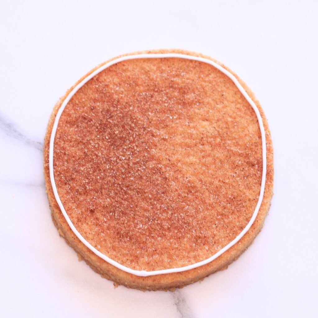 A circular cookie with white icing outlines along the border.