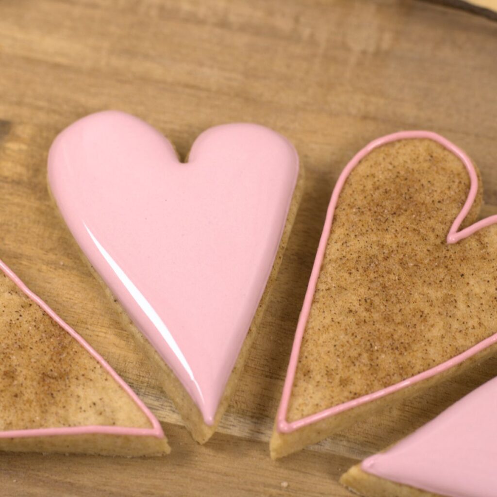 Four cookies, two outline in pink icing, and two completely covered in pink icing.